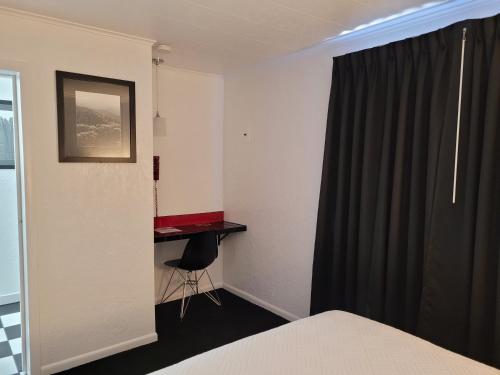a room with a bed and a desk and a window at Rocket Motel in Custer