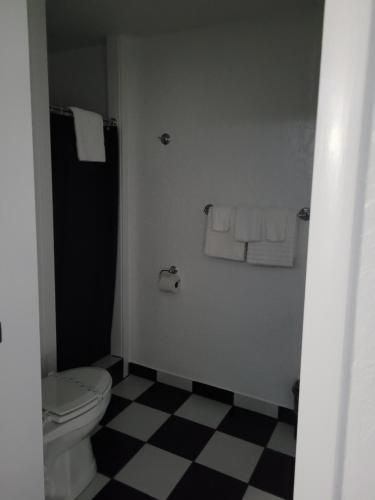 a bathroom with a toilet and towels on a checkered floor at Rocket Motel in Custer