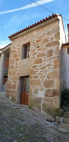 a stone building with a brown door on it at Casa Cereja in Pêro Viseu