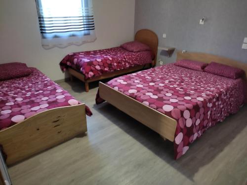 two beds in a room with pink sheets at GITE DE L'ORCHIDÉE P M r in Locmaria-Grand-Champ