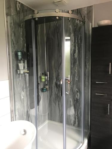 a shower with a glass door in a bathroom at Roselea in Glasbury