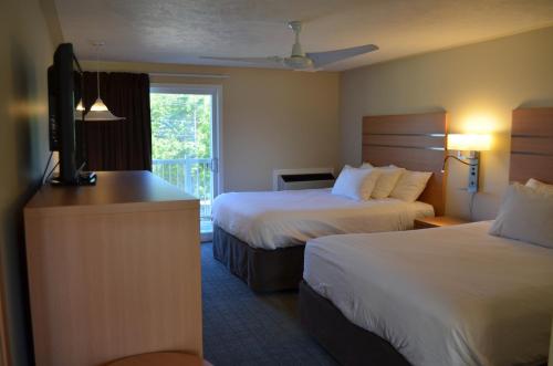 a hotel room with two beds and a flat screen tv at Bruce Anchor Motel and Cruises in Tobermory
