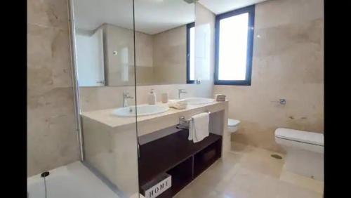 a bathroom with a sink and a toilet and a mirror at Urb Jardines de Sotogrande dúplex, 120 m2, Piscina in Sotogrande