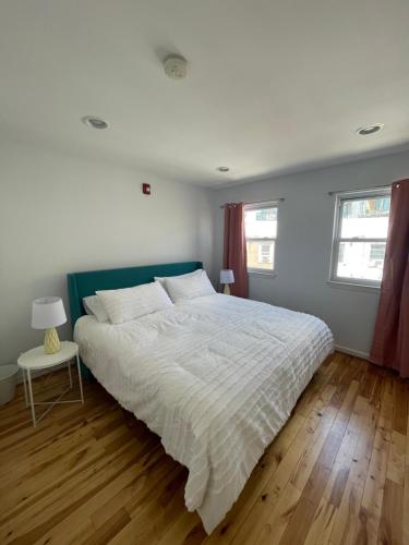 a bedroom with a large white bed and two windows at The Fillmore Point Northern Liberties/Fishtown in Philadelphia