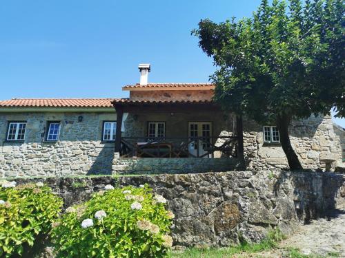 a stone house with a stone wall and a tree at Casa do Sapateiro - piscina in Valença