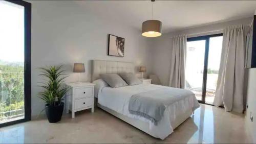 Un dormitorio blanco con una cama grande y una ventana en Urb Jardines de Sotogrande dúplex, 120 m2, Piscina, en Sotogrande