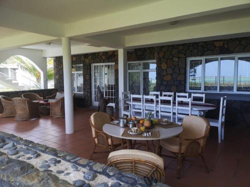 a restaurant with tables and chairs and windows at Villa Karel Mauritius Beach house in Riambel