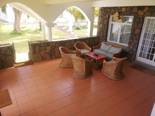a porch with wicker chairs and a table at Villa Karel Mauritius Beach house in Riambel