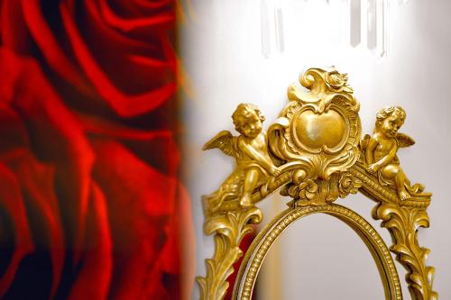 a gold mirror with two children on it next to a red curtain at La Rose Residence in Mikołajki