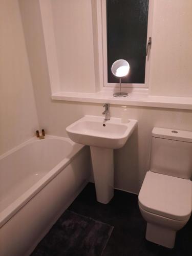 a bathroom with a sink and a toilet and a bath tub at Ardfern Apartments in Airdrie