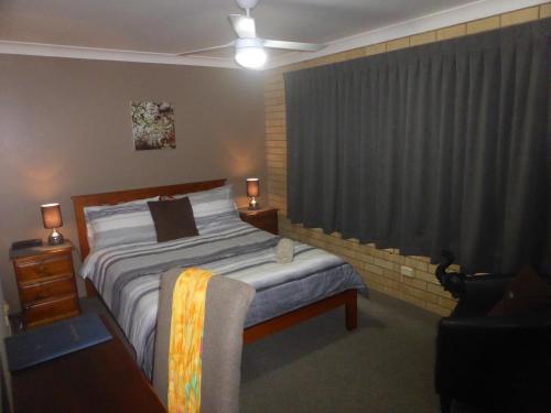 Un dormitorio con una cama y una ventana con cortinas. en The Edge Guest Rooms, en Goonellabah