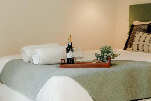 a bottle of wine and two glasses on a bed at JARS Apartments - Casa do Bessa in Porto