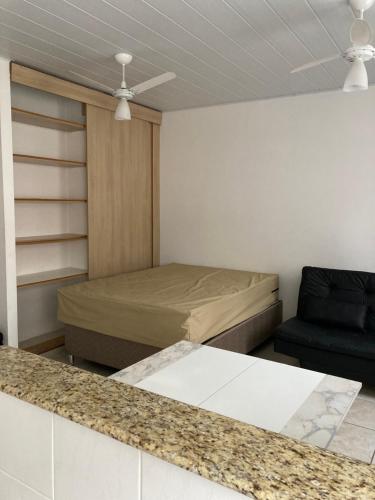 een kleine kamer met een bed en een stoel bij Aconchegante studio frente mar com vista CANTO DO FORTE in Praia Grande