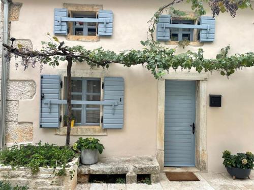 une maison avec des fenêtres à volets bleus et un banc dans l'établissement Loft by Villa di Piazza - a home you won’t forget, à Višnjan