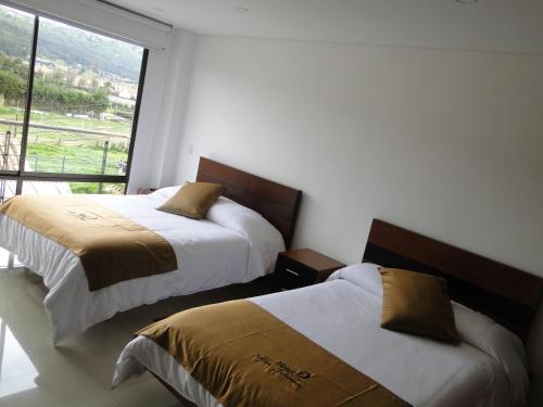 two beds in a room with a window at Hotel Campestre Villa Juliana in Chía