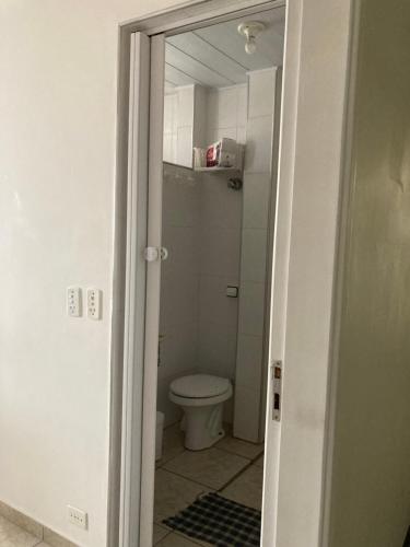 een badkamer met een toilet en een deur open bij Aconchegante studio frente mar com vista CANTO DO FORTE in Praia Grande