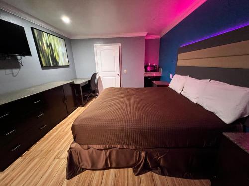 BELL RESORT MOTEL في Bell: غرفة نوم بسرير كبير مع اضاءة ارجوانية
