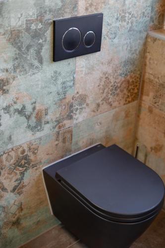a black toilet in a bathroom with a wall at Rooms21 in Schiefling am See