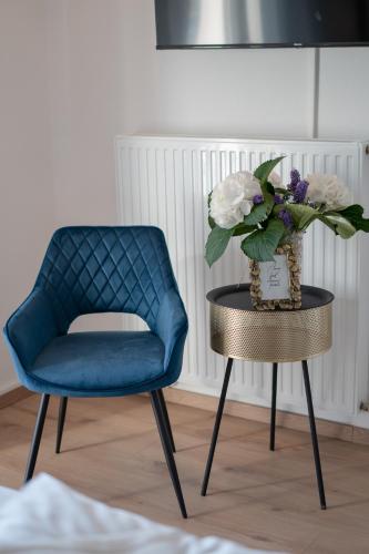 a blue chair and a table with a vase of flowers at Rooms21 in Schiefling am See