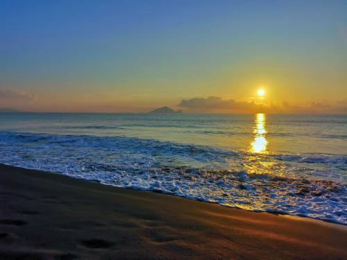 una puesta de sol en una playa con el océano en 秒飛日本 頭城小京都町家溫泉之宿, en Toucheng