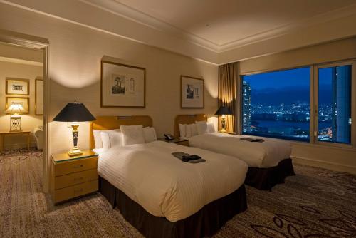 a hotel room with two beds and a large window at Kobe Bay Sheraton Hotel & Towers in Kobe