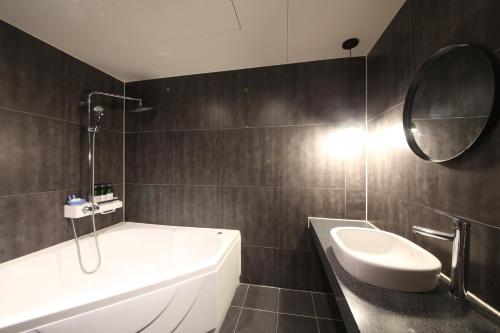 a bathroom with a tub and a sink and a mirror at Hotel Frenchcode in Busan