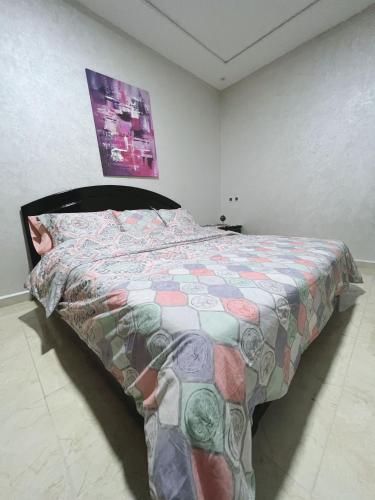a bedroom with a bed with a colorful comforter at Au dix sept in Dakhla