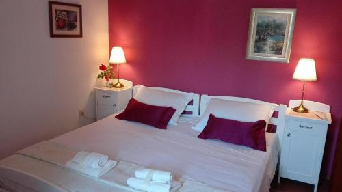 1 dormitorio con 1 cama blanca grande y paredes rojas en Apartments by the sea Milna, Brac - 5242, en Milna