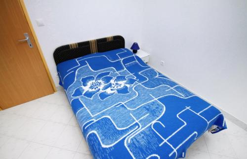 a bed in a room with a blue comforter at Apartments with a parking space Mimice, Omis - 5251 in Mimice
