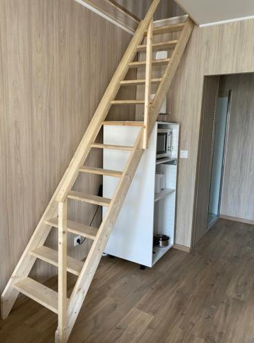 uma escada de madeira num quarto com um frigorífico em Duplex atypique en bois entre ville et verdures em La Chapelle-Saint-Mesmin