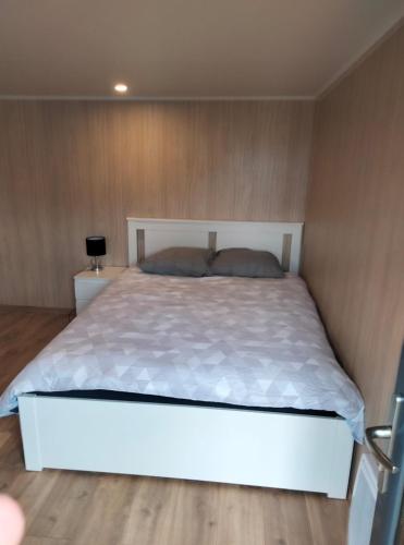 une chambre avec un grand lit blanc et des murs en bois dans l'établissement Duplex atypique en bois entre ville et verdures, à La Chapelle-Saint-Mesmin