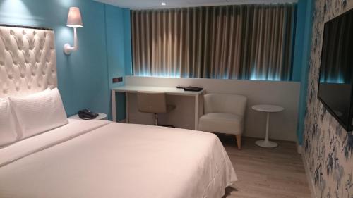 a bedroom with a bed and a desk and a chair at The Cloud Hotel in Taichung