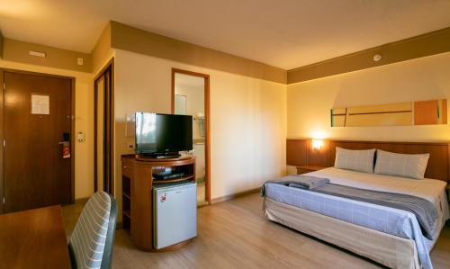 a hotel room with a bed and a flat screen tv at Suíte na região dos hospitais in São Paulo