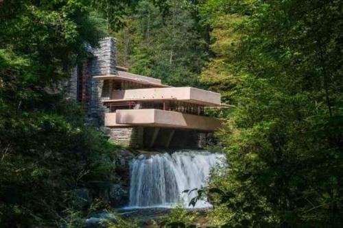 a building on top of a waterfall next to a river at Stay In Ohiopyle near the GAP Trail - Ohiopyle, PA in Ohiopyle