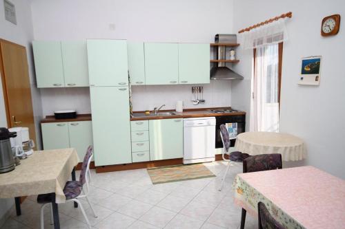 a kitchen with white cabinets and a table and chairs at Triple Room Gornje selo 5170d in Grohote
