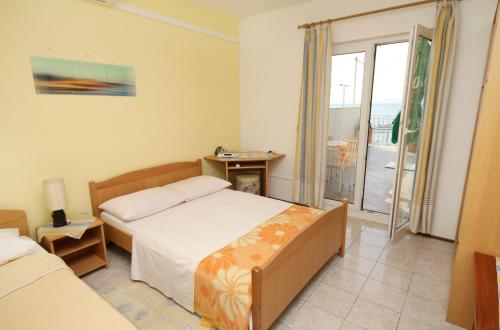 een slaapkamer met een bed en een deur naar een balkon bij Apartments by the sea Duce, Omis - 5275 in Dugi Rat