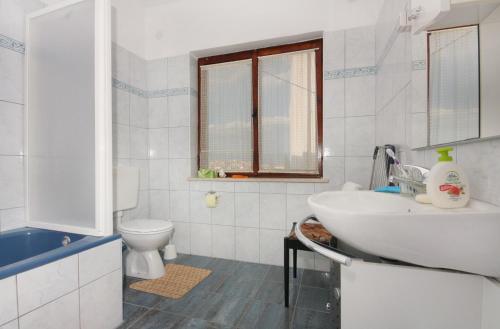 a white bathroom with a sink and a toilet at Apartment Vrbnik 5301b in Vrbnik
