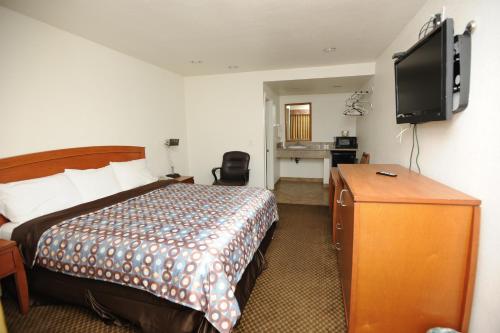 a hotel room with a bed and a flat screen tv at Victoria Motel in Ventura