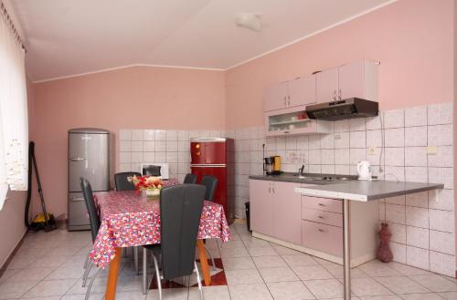 a kitchen with a table and a refrigerator and a table and chairs at Apartments and rooms with parking space Vrbnik, Krk - 5302 in Vrbnik