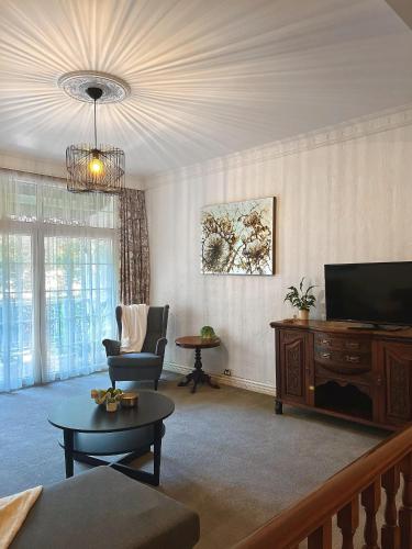 a living room with a tv and a couch and a table at Victoria House Motor Inn in Croydon