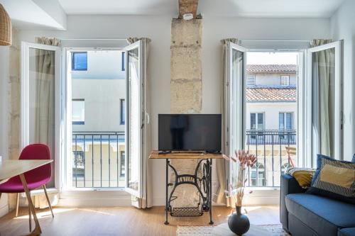 a living room with a tv and two large windows at La Palmeraie - Splendide coeur du Centre-Ville in Marseille