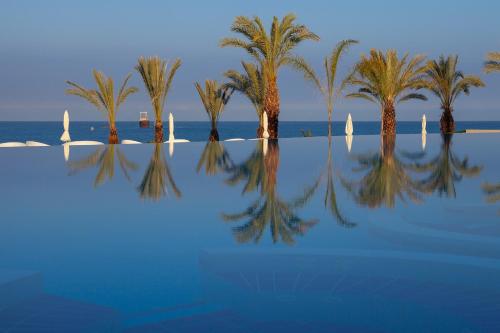 a group of palm trees and the water with sailboats at King Evelthon Beach Hotel & Resort in Paphos City