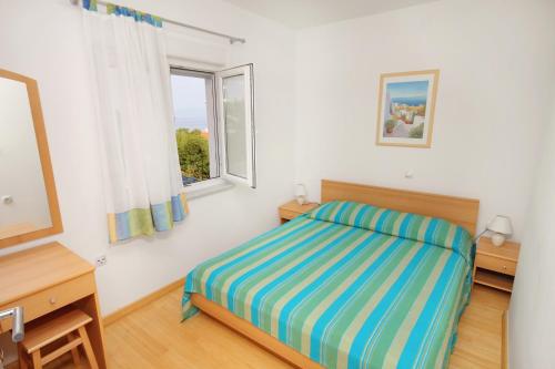 a bedroom with a bed and a window at Apartments by the sea Njivice, Krk - 5296 in Njivice
