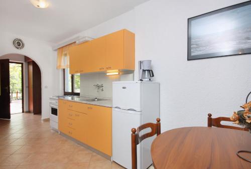 a kitchen with a white refrigerator and a table at Apartments by the sea Njivice, Krk - 5311 in Njivice