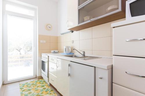 d'une cuisine avec des placards blancs, un évier et une fenêtre. dans l'établissement Apartments and rooms with parking space Krk - 5294, à Krk