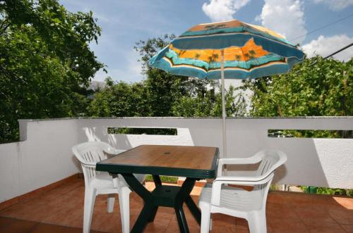 a table and chairs with an umbrella on a patio at Apartments with a parking space Baska, Krk - 5411 in Baška
