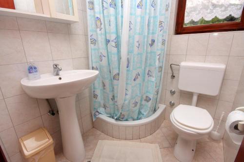 a bathroom with a sink and a toilet and a shower curtain at Apartments with a swimming pool Baska, Krk - 5354 in Baška
