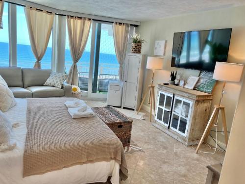 sala de estar con cama y TV de pantalla plana en Beach Oasis 704 Lovely Daytona ocean front for 5 sleeps up to 12, en Daytona Beach