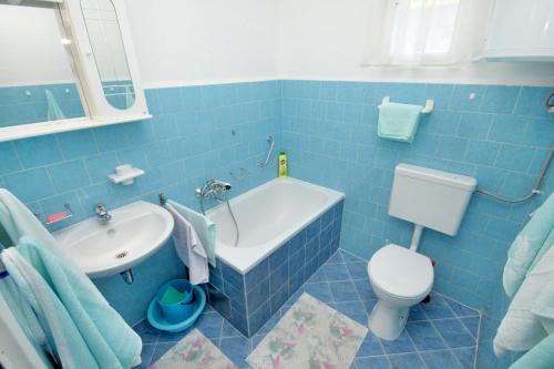 a blue bathroom with a tub and a toilet and a sink at Apartment Krk 5318a in Krk