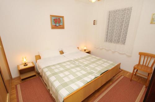 a bedroom with a bed and a wooden chair at Apartments with a parking space Krk - 5318 in Krk